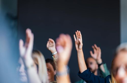Engaged Audience Raising Hands at Business Event