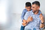 Loving Father and son playing at home on the sofa. They are happy and smiling